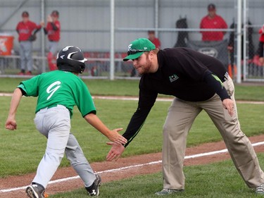 East Nepean Eagles' coach Mark Keeping low-fives Michael Stremlaw after he led off the bottom of the first inning with a solo homer.