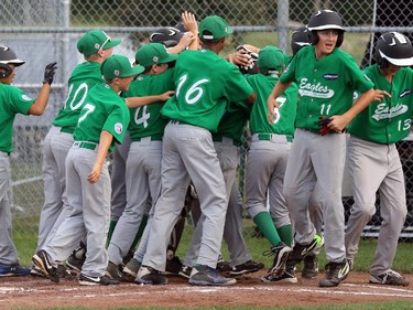 East Nepean Eagles' players surround SS #9 Michael Stremlaw (obscured) after he led off the bottom of the first inning with a solo homer.