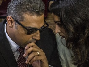 Al-Jazeera journalist Canadian Mohamed Fahmy, accused along with Egyptian Baher Mohamed of supporting the blacklisted Muslim Brotherhood in their coverage for the Qatari-owned broadcaster, talks to human rights lawyer representing him, Amal Clooney during his trial in Cairo on Saturday. The court sentenced Fahmy and Mohamed, along with Australian journalist Peter Greste who was tried in absentia after his deportation early this year, to three years in prison. Fahmy was abruptly pardoned in late September.
