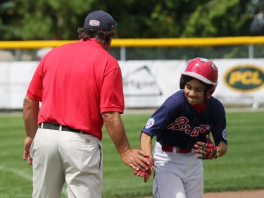 High Park (Toronto) Braves' #25 David Gucciardi low-fives 3B coach Louis Rocha on his way toward home plate after hitting a two-run homer.