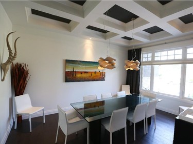 The formal dining room with coffered ceiling and live sawn red oak floor. The soft, organic shape of the birdseye maple-veneer ceiling lights from Arevco, like the rounded chairs and floor vase, contrast with the room’s linear design. The painting is by Canadian artist Edouard Ambrose, one of the Staples’ favourites. All main-floor ceilings are 10 feet; lower level ceilings are nine feet.