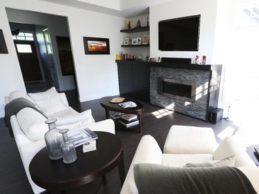 Natural daylight floods the great room, where the kitchen’s black-and-white theme is echoed. The couch and chair lend a traditional touch to the room’s contemporary design. Visible in the background is the main foyer and the hallway leading to the children’s wing and stairs to the lower level.