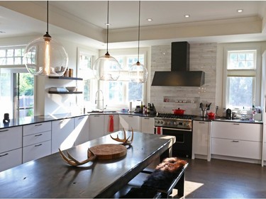 The custom-made rustic, alder table features bearskin-covered benches, a centrepiece of antlers and wooden serving board, and, above, a trio of pendant lamps from Arevco Lighting. 'There’s enough room to sit at least 10 people comfortably,' says Julie. 'It’s nice to sit there with friends and chat or just have a glass of wine.' The rustic table contrasts pleasingly with the sleek modern kitchen.