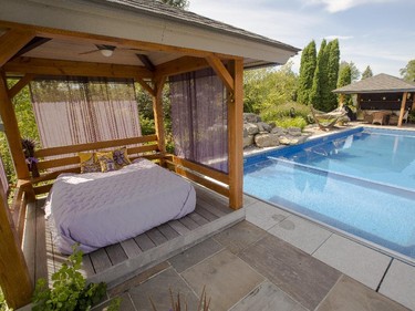 Made of western red cedar and a tad whimsical, the poolside pavilion with its raised floor and curtained walls met the client’s wish for a shaded getaway area. At the other end of the pool are a more socially inclined outdoor kitchen, covered sitting area and hot tub.