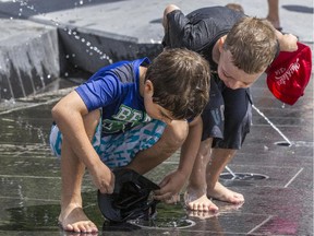 Joao Vitor and Daniel Weinstein, both 6, fill their hats with water at Lansdowne's water plaza.