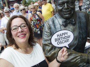 Kelly Peterson sits beside the statue of her late husband, Oscar Peterson, during the celebration of what would have been his 90th birthday on Saturday, Aug. 15, 2015.