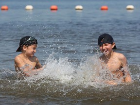 Nico Martinez has a water fight with his brother Mateo Monday at Petrie Island beach. Ottawa's municipal beaches remain open, but without life guard supervision or daily water-quality testing.