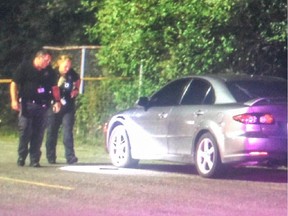 Police look at a Mazda in the Brookfield High School parking lot on the night of Sunday, Aug. 2 after the 22nd Ottawa shooting of 2015.