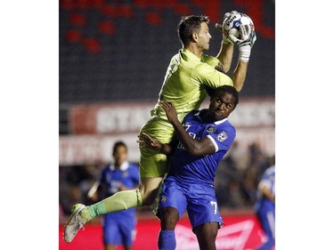 Ottawa Fury's goalkeeper Romuald Peiser (1) grabs the ball overtop New York Cosmos' Lucky Mkosana (77).