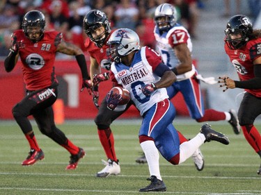 Stefan Logan #0 of the Montreal Alouettes runs the ball to score a touchdown as members of the Ottawa Redblacks attempt to catch him.