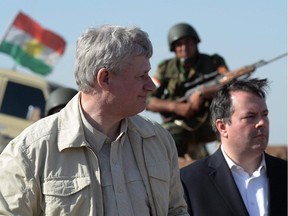 A Kurdish soldier sits in the background as Prime Minister Stephen Harper and Minister of Defence Jason Kenney visit members of the Advise and Assist mission, approximately 6 kilometres from active ISIL fighting positions, near Erbil, Iraq, on Saturday, May 2, 2015. During the writ period, there is a blackout on media briefings about the anti-ISIL mission.