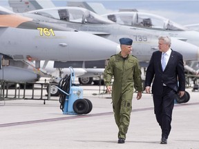 Stephen Harper, right, walks by CF18 jet fighters with Col. Sylvain Menard at CFB Bagotville back in June.