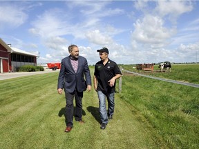 NDP Leader Tom Mulcair, left, speaks with dairy farmer Pedro Slits at the Slits Dairy Farm in Brunner, Ont., on Wednesday, July 22, 2015.
