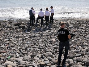 Police officers inspect metallic debris found on a beach in Saint-Denis on the French Reunion Island in the Indian Ocean on August 2, 2015, close to where where a Boeing 777 wing part believed to belong to missing flight MH370 washed up last week.