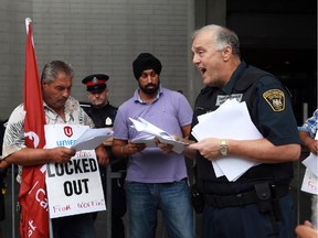 Under the watchful eye of police, Terry Kilrea reads the injunction to cabbies at the Ottawa airport, Saturday, August 15, 2015. This morning, an injunction was served limiting the number of taxicabs and drivers that can protest at (and around) the airport. Mike Carroccetto / Ottawa Citizen
