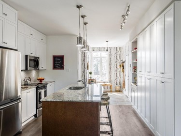 The entryway opens to a full-width kitchen with timeless white Shaker cabinets, a generous island topped in granite (a standard feature) and a long wall of pantry cupboards.