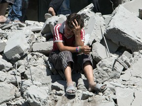 A young Syrian boy cries as he sits on the rubble after a missile fired by Syrian government forces hit a residential area in the Maghayir district in the old quarter of the northern Syrian city of Aleppo on July 21, 2015. According to the Syrian Observatory of Human Rights more than 35 homes were destroyed in the attack killing at least 18 civilians, adding that the death toll was likely to rise. AFP PHOTO / KARAM AL-MASRIKARAM AL-MASRI/AFP/Getty Images