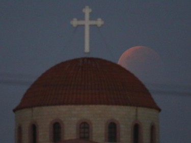 A "blood moon", casts its glow over a Christian Orthodox church in Anthoupolis, a suburb of Nicosia in the early hours of Monday, Sept. 28, 2015. A lunar eclipse has given the moon a red tint and makes it appear larger than usual. The rare confluence of an eclipse and supermoon won't happen again for 18 years.