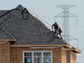 A construction worker shingles the roof of a new home in a development in Ottawa on July 6, 2015.