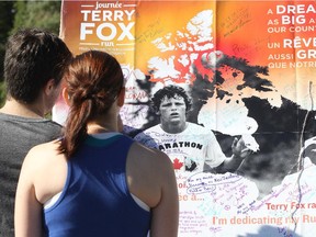 A couple read the various dedication messages written on the Terry Fox poster during the annual Terry Fox Run in Ottawa on September 20, 2015.