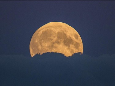 A full moon rises between clouds in Berlin, Germany, Sunday, Sept. 27, 2015. The full moon was seen prior to a phenomenon called a "Super Moon" eclipse that will occur during moonset on Monday morning, Sept. 28.