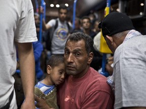 A man and a child ride aboard a bus provided by Hungarian authorities for migrants and refugees at Keleti train station in Budapest, Hungary, Saturday, Sept. 5, 2015. Hundreds of migrants boarded buses provided by Hungary's government as Austria in the early-morning hours said it and Germany would let them in. Austrian Chancellor Werner Faymann announced the decision early Saturday after speaking with Angela Merkel, his German counterpart - not long after Hungary's surprise nighttime move to provide buses for the weary travelers from Syria, Iraq and Afghanistan.
