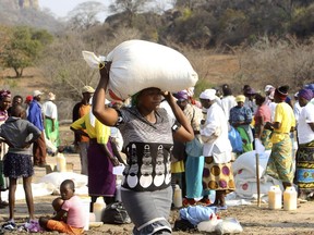 A woman carries a bag of maize distributed by the United Nations World Food Programme (WFP) in Mwenezi, about 450 kilometers (280 miles) south of Harare, Zimbabwe, Wednesday, Sept. 9 2015. According to the United Nations and the Zimbabwean government some about 1.5 million people face severe food shortages due to a consecutive bad harvests and poor rains.