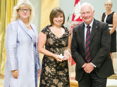 Amanda Troupe from the Treasury Board of Canada Secretariat, center, receives the Public Service Award of Excellence on behalf of the Career Boot Camp 2015 Steering Committee for Employee Innovation from Janice Charette, clerk of the privy council, left, and David Johnston, Governor General of Canada, right, at Rideau Hall Wednesday September 16, 2015. (Darren Brown/Ottawa Citizen) - Assignment 121627