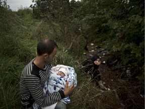 Syrian refugee Raed Alabdou, 24, holds his one-month-old daughter, Roa'a, while he and his wife hide in a field from Hungarian police after they crossed the Serbian-Hungarian border near Roszke, southern Hungary, Friday, Sept. 11, 2015.