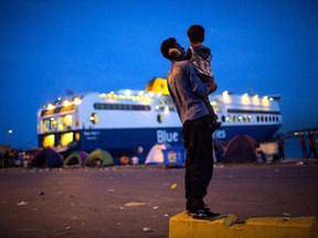 A refugee holds a child near a ferry at the port of Mytilini on Sept. 9, 2015 in Lesbos, Greece.