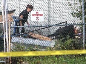City police identification officers search through a fenced-in yard behind 330 Division St. Tuesday, Sept. 29, 2015 in Kingston, Ont.