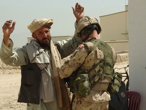 Master Corporal Collin Fitzgerald searches an Afghan man prior to entering the Afghan National Police compound in this supplied photo.