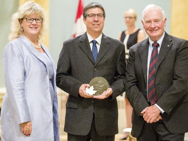 Eric Irissou from the National Research Council of Canada, center, receives the Public Service Award of Excellence on behalf of the Cold Spray Additive Manufacturing Team for Employee Innovation from Janice Charette, clerk of the privy council, left, and David Johnston, Governor General of Canada, right, at Rideau Hall Wednesday September 16, 2015. (Darren Brown/Ottawa Citizen) - Assignment 121627