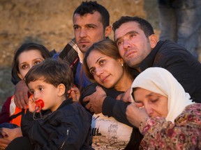 In this Aug. 13, 2015 file photo, a family of refugees hug each other after successfully arriving on a dinghy on the Greek island of Kos after crossing overnight from Turkey to Greece. Greece has become the main gateway to Europe for tens of thousands of refugees and economic migrants, mainly Syrians fleeing war, as fighting in Libya has made the alternative route from north Africa to Italy increasingly dangerous.