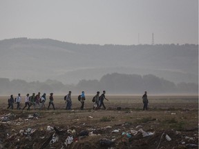 Syrian refugees walk through a field near the border town of Idomeni in northern Greece to cross into Macedonia on Aug. 26. The UN's refugee agency said it expects 3,000 people to cross Macedonia daily in the coming days as Greece has borne the brunt of a record number of refugees and migrants heading to Europe.