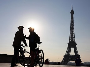 Picture taken early in the morning on September 27, 2015 shows two men with bikes chating in front of the Eiffel Tower.