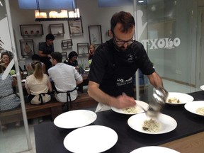 Chef Bendur Elizondo plates rice with clams and cod while behind him,  San Sebastian Food cooking class students dig in to a Basque feast.