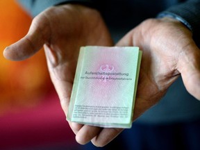 A man from Syria displays his temporary residency permit for the time of his asylum process at the home for refugees in Hohenmoelsen, eastern Germany on September 10, 2015.  Around 450,000 refugees have arrived in Germany so far this year, including 37,000 in the first eight days of September, Vice Chancellor Sigmar Gabriel told parliament.