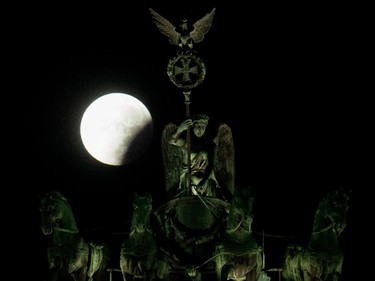 A so-called "super moon" can be seen behind the Quadriga sculpture on top of Berlin's landmark the Brandenburg Gate during a total lunar eclipse on September 28, 2015. Skygazers were treated to a rare astronomical event when a swollen "supermoon" and lunar eclipse combined for the first time in decades, showing Earth's satellite bathed in blood-red light.