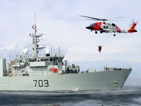 A United States Coast Guard (USCG) H-60 Jayhawk helicopter from Air Station Sitka, Alaska, hovers over the deck of HMCS EDMONTON as a USCG rescue swimmer and Royal Canadian Air Force search and rescue technician are hoisted on board during a search and rescue exercise held on April 30, 2013, off the coast of Prince Rupert, B.C.