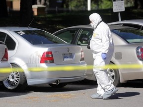 Hours after a teen was stabbed to death, a police forensics ID officer takes photos of blood splatter on a car parked in front of 2000-2020 Jasmine Cres. in on Sunday, September 20, 2015. A 17-year-old teen is dead and two others are in hospital.