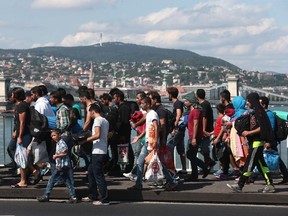 Hundreds of migrants walk on the Elisabeth Bridge after leaving the transit zone of the Budapest main train station, on September 4, 2015 intent on walking to the Austrian border. They were part of an estimated 2,000 migrants stuck in makeshift refugee camps at Keleti station, after railway authorities had blocked them from boarding trains to Austria and Germany.