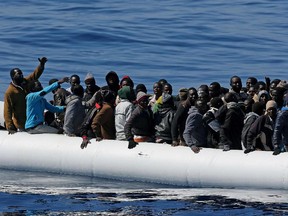 Migrants crowd and inflatable dinghy as rescue vessel Denaro (not in picture) of the Italian Coast Guard approaches them, off the Libyan coast, in the Mediterranean Sea, Wednesday, April 22, 2015.  Italy pressed the EU on Wednesday to devise robust steps to stop the deadly tide of migrants crossing the Mediterranean, including considering military intervention against smugglers and boosting U.N. refugee offices in countries bordering Libya.