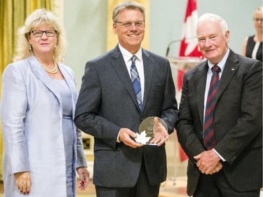 Jacques Paquette from Employment and Social Development Canada, center, receives the Public Service Award of Excellence, The Joan Atkinson Award, from Janice Charette, clerk of the privy council, left, and David Johnston, Governor General of Canada, right, at Rideau Hall Wednesday September 16, 2015. (Darren Brown/Ottawa Citizen) - Assignment 121627