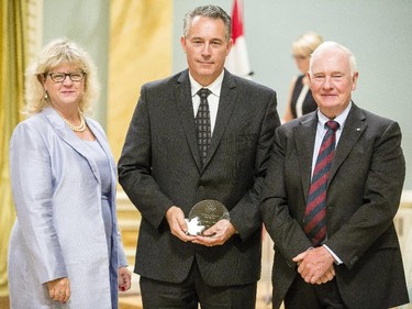 Jeffrey Mills of Correctional Services Canada, center, receives the Public Service Award of Excellence for Scientific Contribution from Janice Charette, clerk of the privy council, left, and David Johnston, Governor General of Canada, right, at Rideau Hall Wednesday September 16, 2015. (Darren Brown/Ottawa Citizen) - Assignment 121627