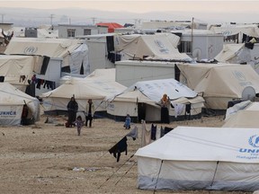 A file picture taken on January 11, 2015, shows Syrian refugees standing next to tents at the UN-run Zaatari refugee camp, north east of the Jordanian capital Amman.