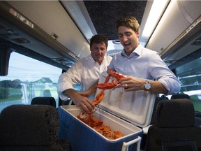 Liberal Leader Justin Trudeau and local candidate Dominic LeBlanc bring a cooler of lobster onto the media bus just outside Neguac, N.B., Tuesday.
