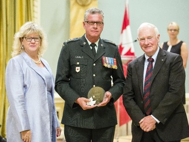 Luc St. Denis of National Defence, center, receives the Public Service Award of Excellence on behalf of the Canadian Armed Forces Arctic Training Centre Team for Employee Innovation from Janice Charette, clerk of the privy council, left, and David Johnston, Governor General of Canada, right, at Rideau Hall Wednesday September 16, 2015. (Darren Brown/Ottawa Citizen) - Assignment 121627