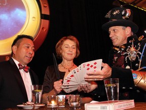 Magician Lawrence Larouche gives Dr. Marjorie Robb a knife to cut the deck of cards, with Dr. Jose Aquino watching on, at the University of Ottawa Faculty of Medicine's Abracadabra: A Night of Magic and Medicine, held Saturday, September 12, 2015, at The Westin Ottawa.