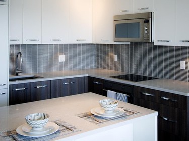 The kitchen of the one-bedroom, like all units, features integrated European appliances and an island/eating bar with storage space. Cabinetry is sleek white uppers and grained brown lowers with stainless-steel hardware.